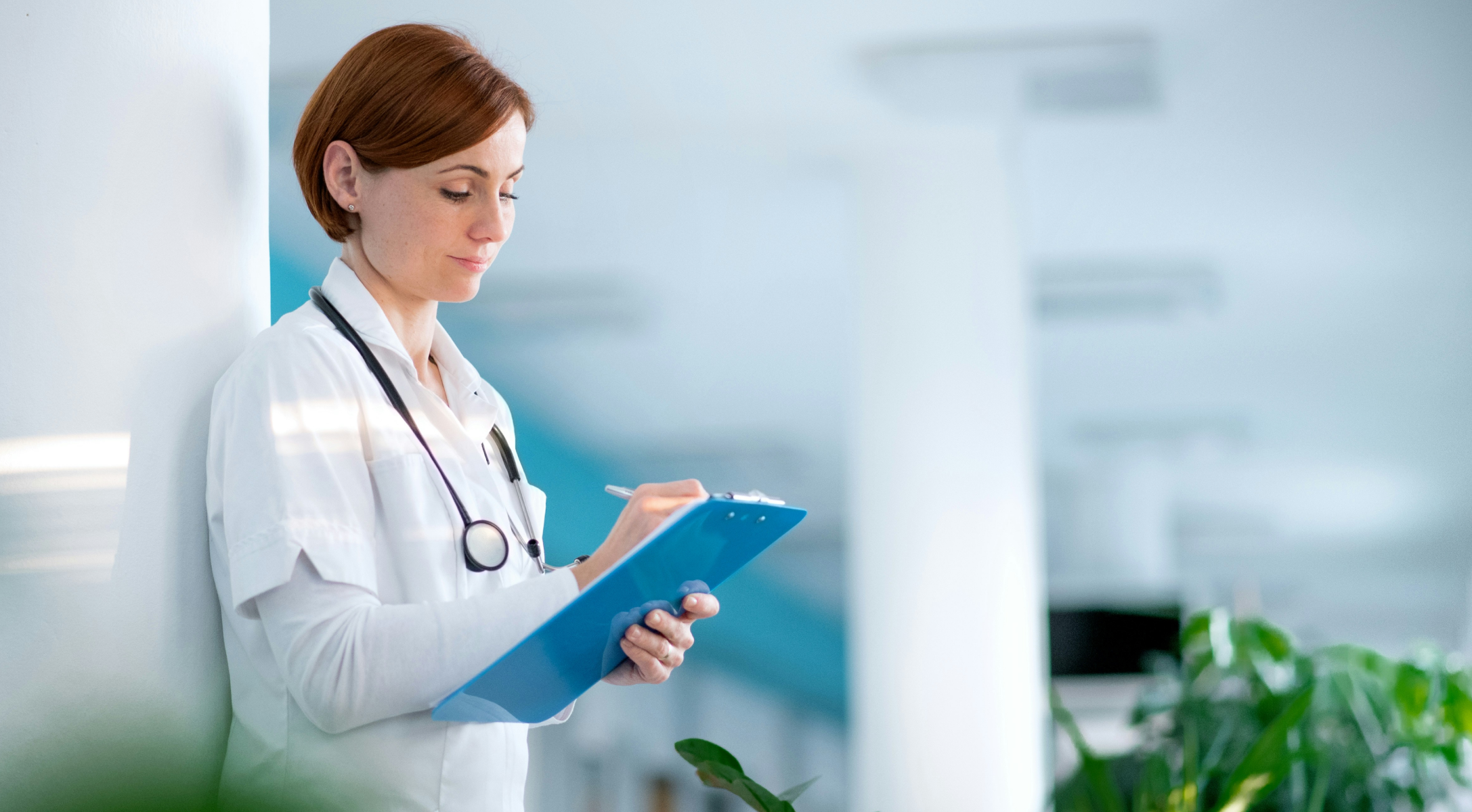 Pracownik ochrony zdrowia trzyma dokumenty w przestrzeni placówki medycznej.