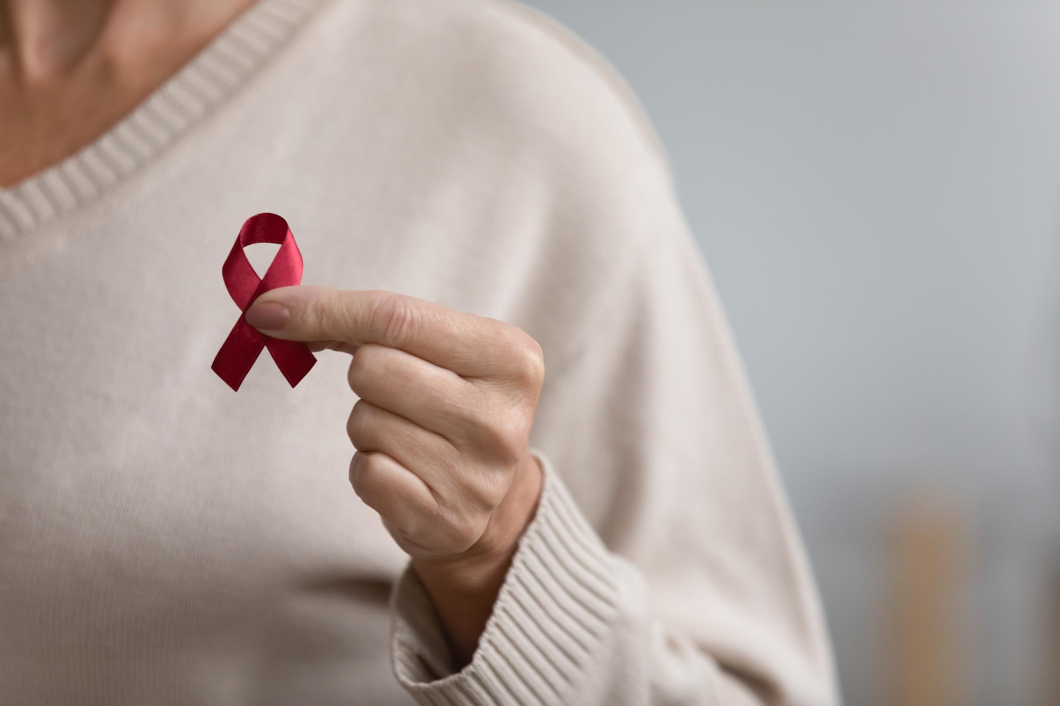 Kobieta w symbolicznym geście solidarności trzyma wstążeczkę onkologiczną