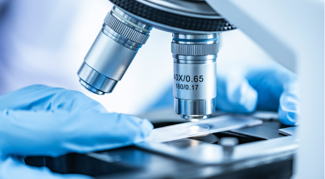 Zbliżenie na mikroskop laboratoryjny i szkiełko z próbką.