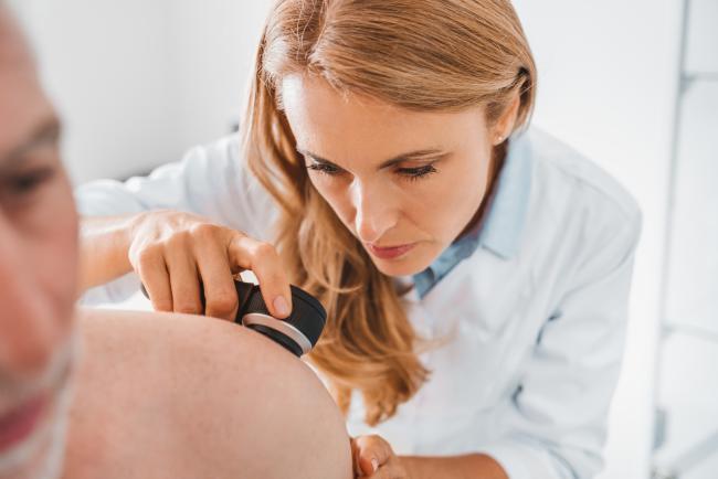Dermatolog ogląda skórę pacjenta przy pomocy specjalistycznego urządzenia